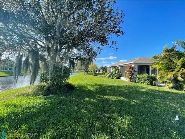 a view of a house with a big yard plants and large trees