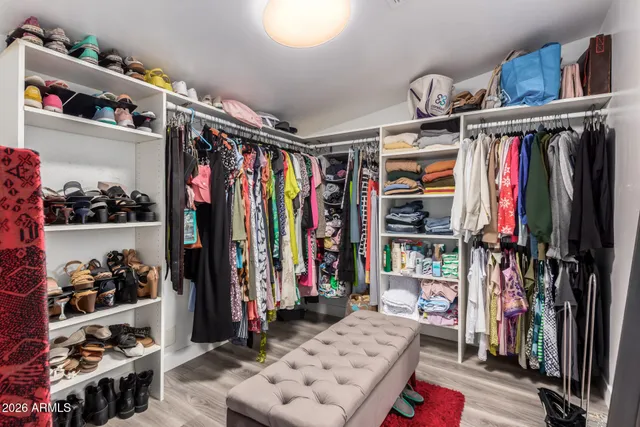 a view of walk in closet with clothes and shoes