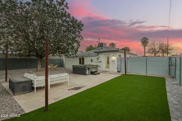 a view of a backyard with couches plants and large trees