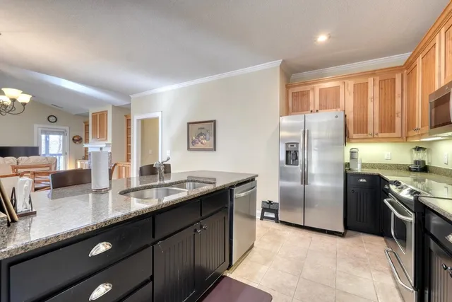 a kitchen with granite countertop a refrigerator a sink a stove a counter space and cabinets