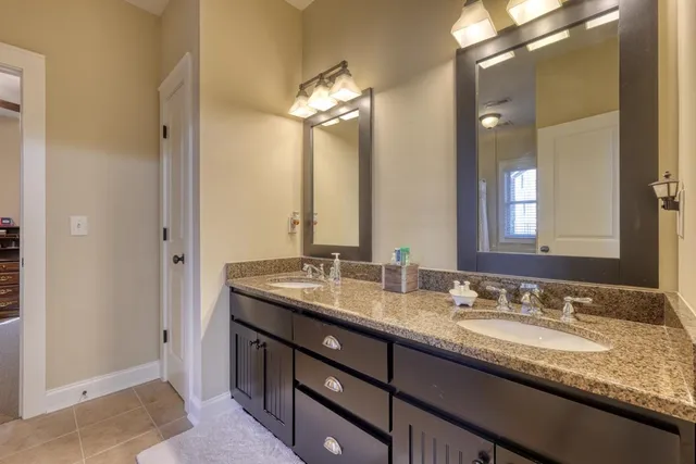 a bathroom with a granite countertop double vanity and a mirror