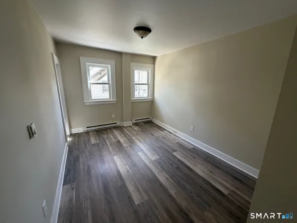 a view of an empty room with wooden floor and a window