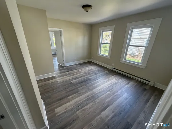 a view of an empty room with wooden floor and a window