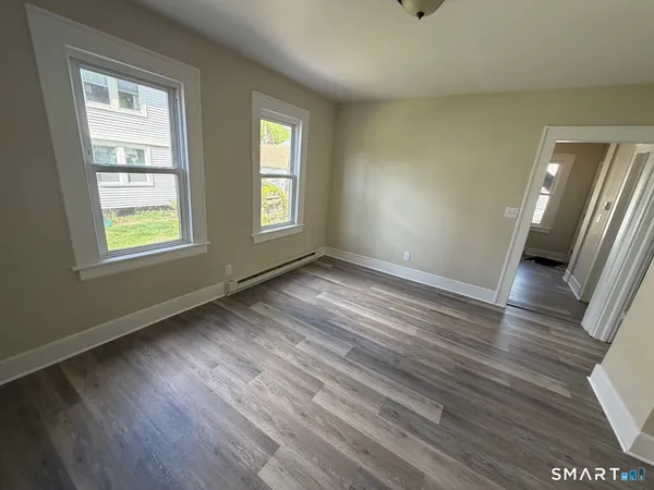 a view of an empty room with wooden floor and a window