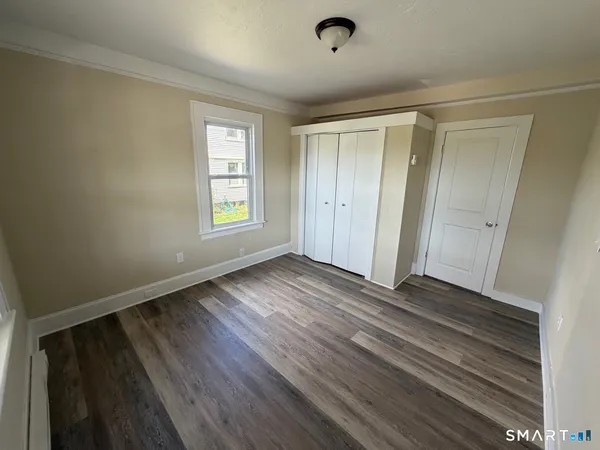 a view of an empty room with window and wooden floor