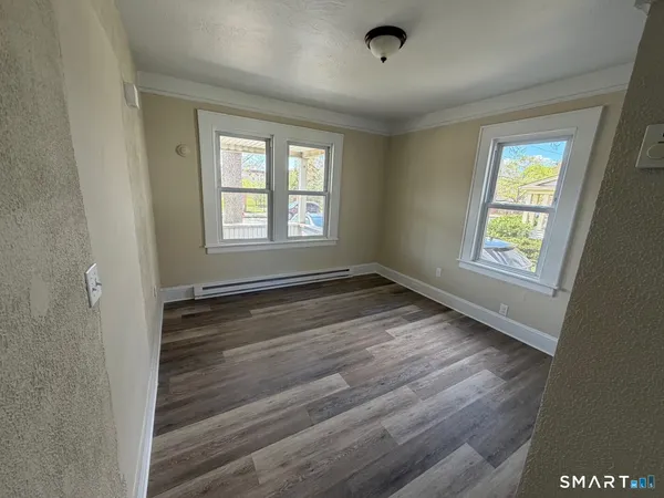 a view of an empty room with wooden floor and a window
