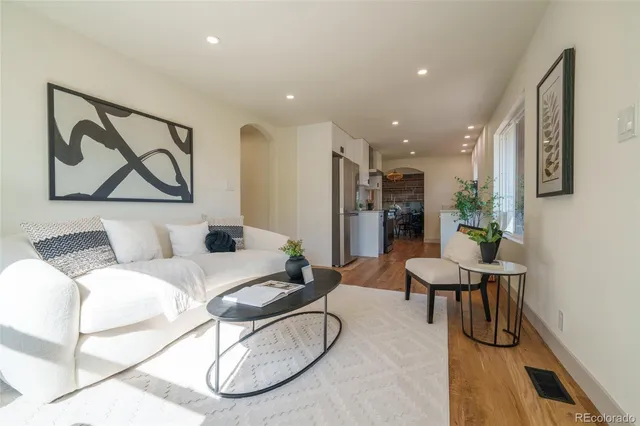 a living room with furniture a refrigerator and kitchen view