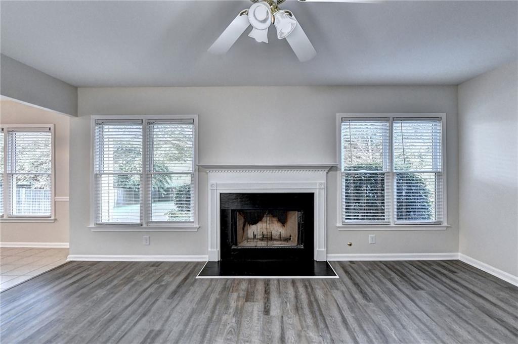 3460 Maple Terrace Drive Suwanee, GA 30024 - Photo 14 of 51 an empty room with wooden floor fireplace cabinet and windows