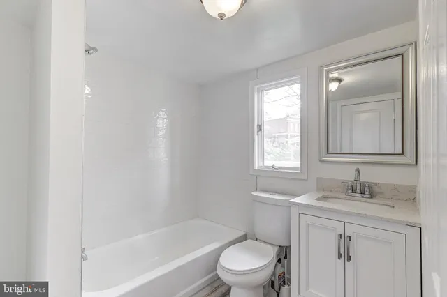 a bathroom with a bathtub shower sink vanity mirror and toilet