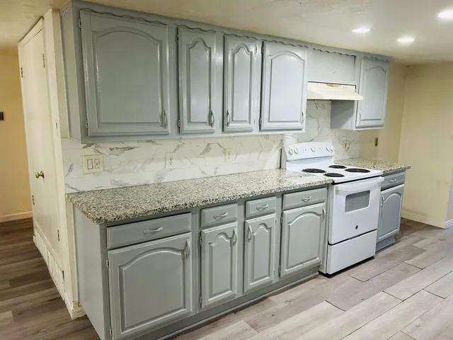 a kitchen with granite countertop a sink stove and cabinets