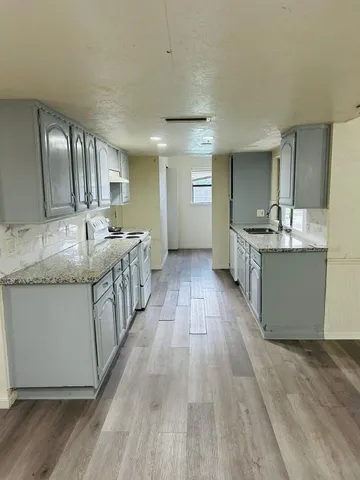a large kitchen with stainless steel appliances kitchen island granite countertop a large counter top and wooden floors