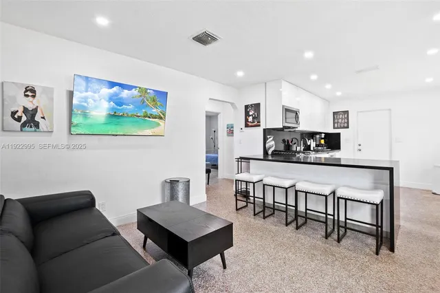 a living room with stainless steel appliances furniture and a flat screen tv
