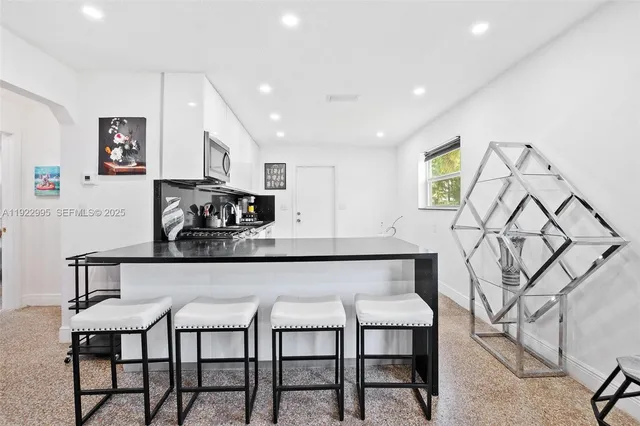 a kitchen with stainless steel appliances granite countertop a table chairs in it and wooden floors