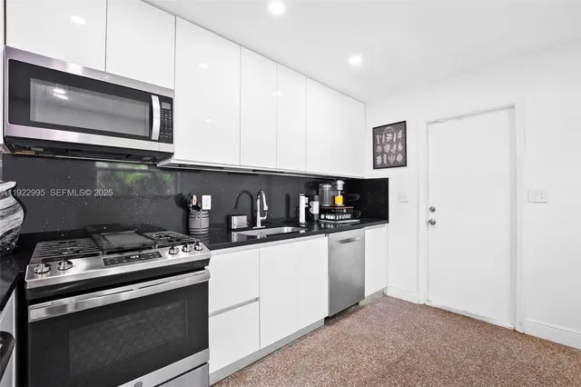 a kitchen with stainless steel appliances a stove microwave and sink