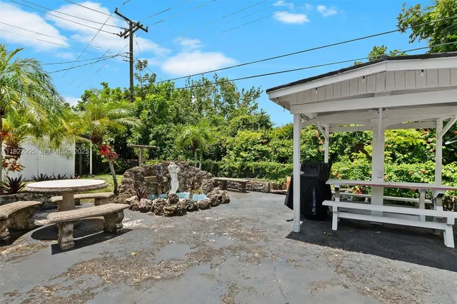 a view of a patio with table and chairs potted plants and a large tree