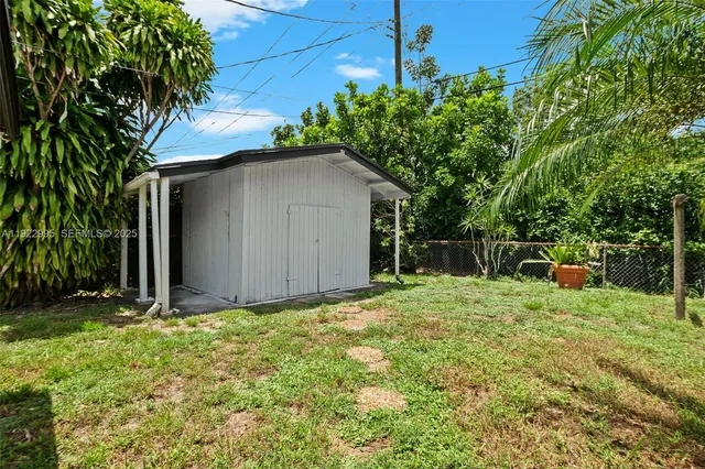 a backyard of a house with plants and large tree