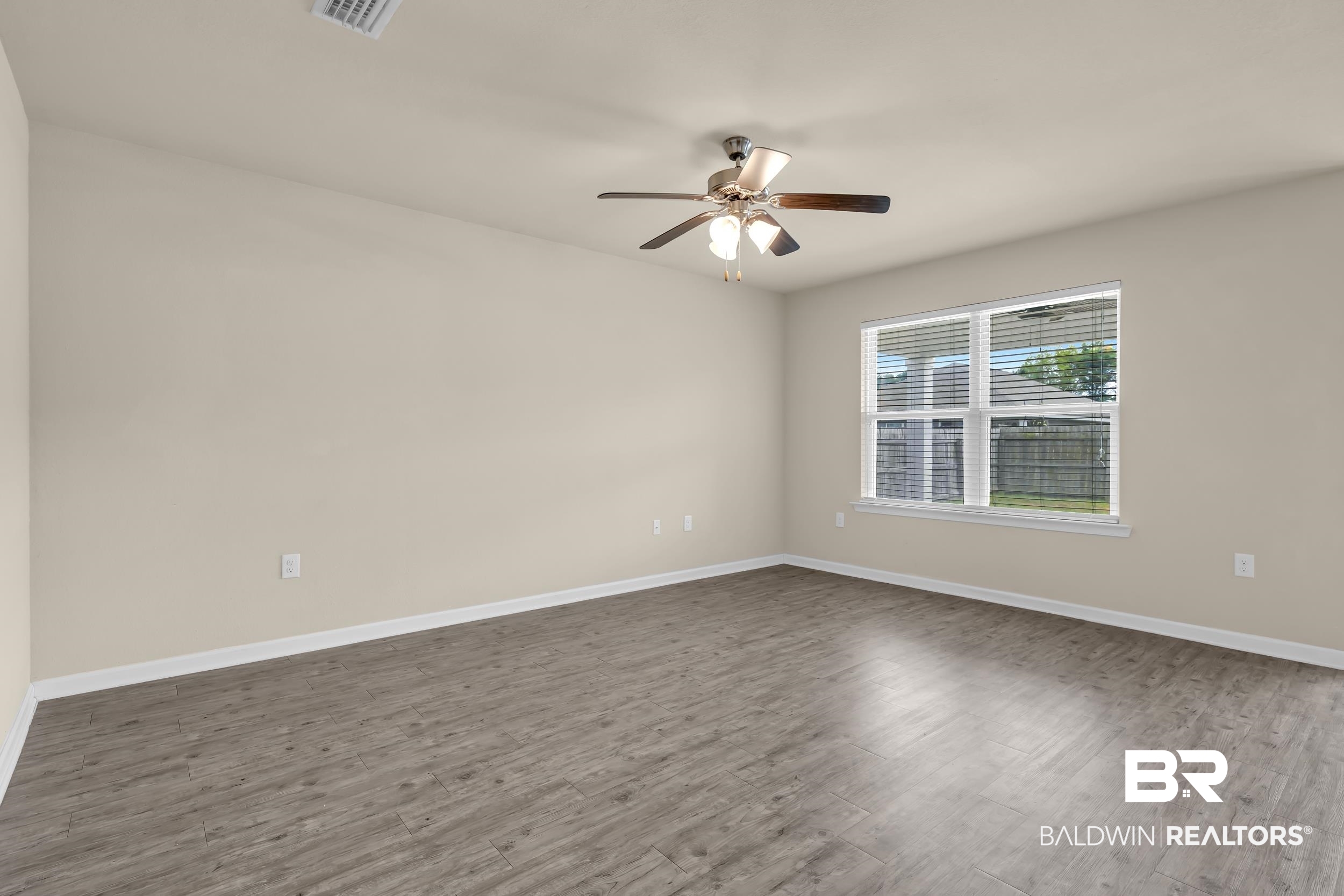 17344 Harding Drive Foley, AL 36535 - Photo 12 of 46 Spacious room featuring neutral painted walls, wood-finish flooring, a ceiling fan with integrated lighting, and a large window with horizontal blinds