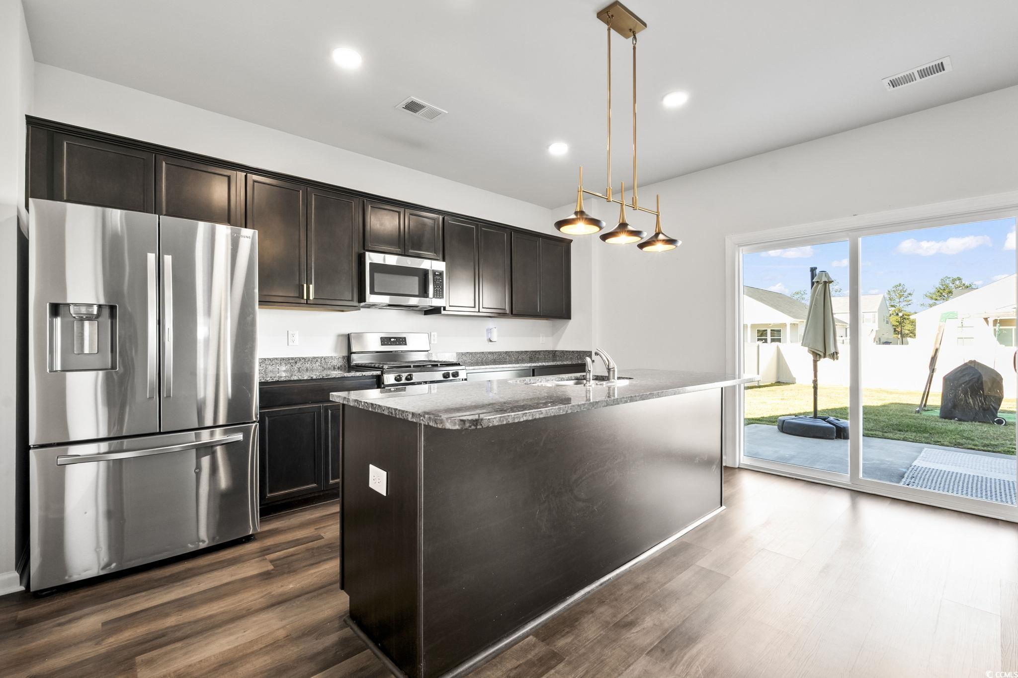 733 Lambeth Lane Conway, SC 29526 - Photo 13 of 40 Kitchen with stainless steel appliances, an island with sink, dark wood-style flooring, decorative light fixtures, and dark brown cabinetry