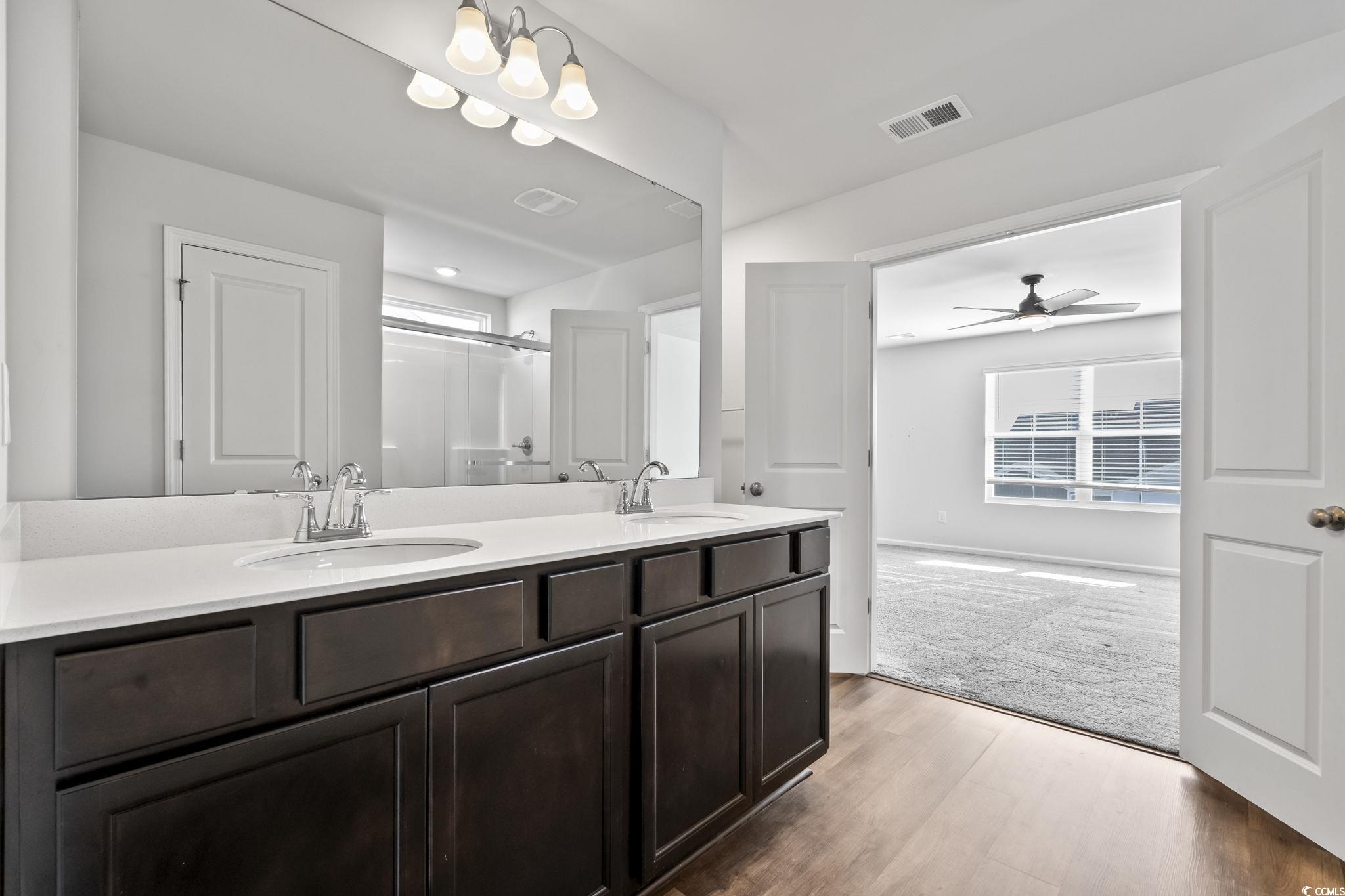 733 Lambeth Lane Conway, SC 29526 - Photo 34 of 40 Bathroom featuring double vanity, a stall shower, light wood-style flooring, a ceiling fan, and light colored carpet