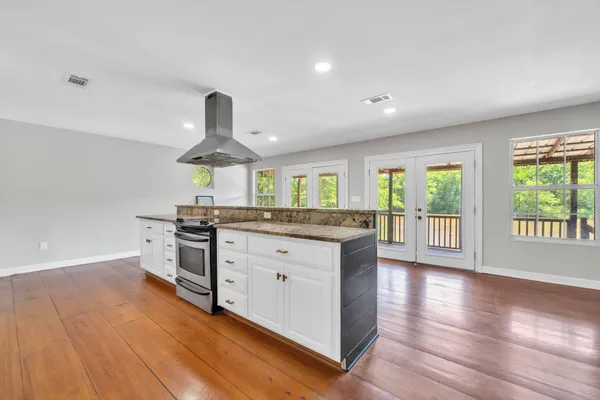 a kitchen with stainless steel appliances granite countertop a refrigerator a sink dishwasher a oven and a dining table with wooden floor