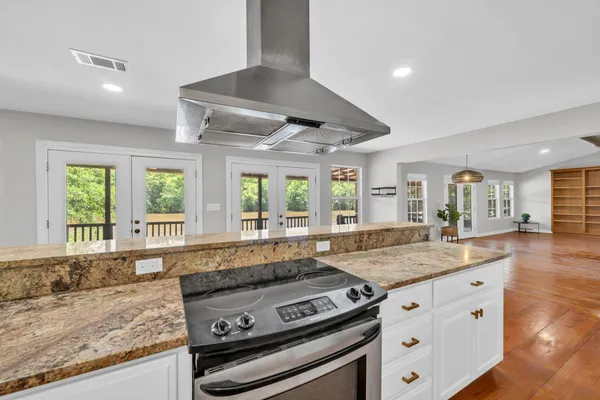 a large kitchen with granite countertop a sink and dishwasher a stove top oven with wooden floor