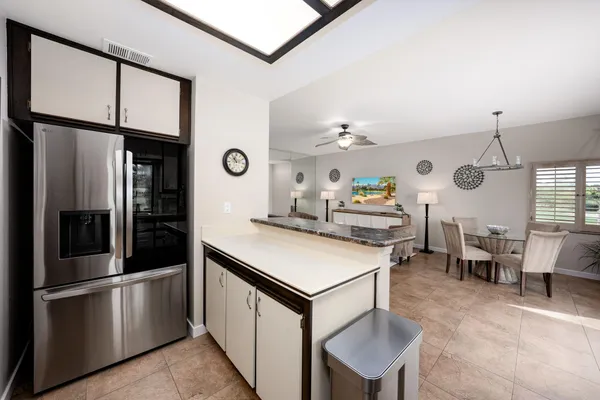 a kitchen with stainless steel appliances granite countertop a stove a refrigerator a dining table and chairs with wooden floor
