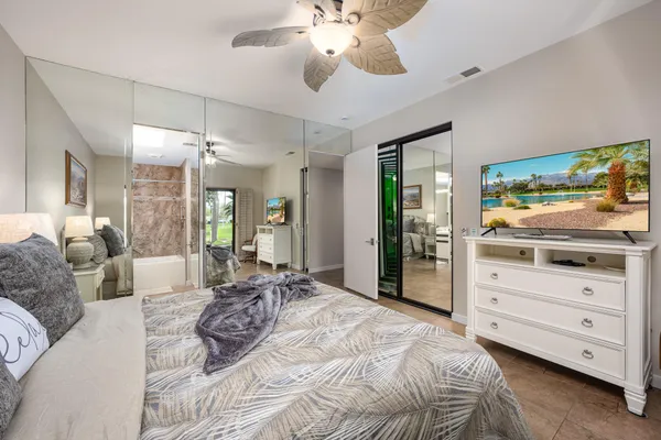 a spacious bedroom with a bed a large mirror and furniture