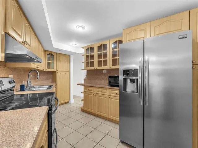 a kitchen with stainless steel appliances granite countertop a refrigerator a stove and a sink with wooden floor
