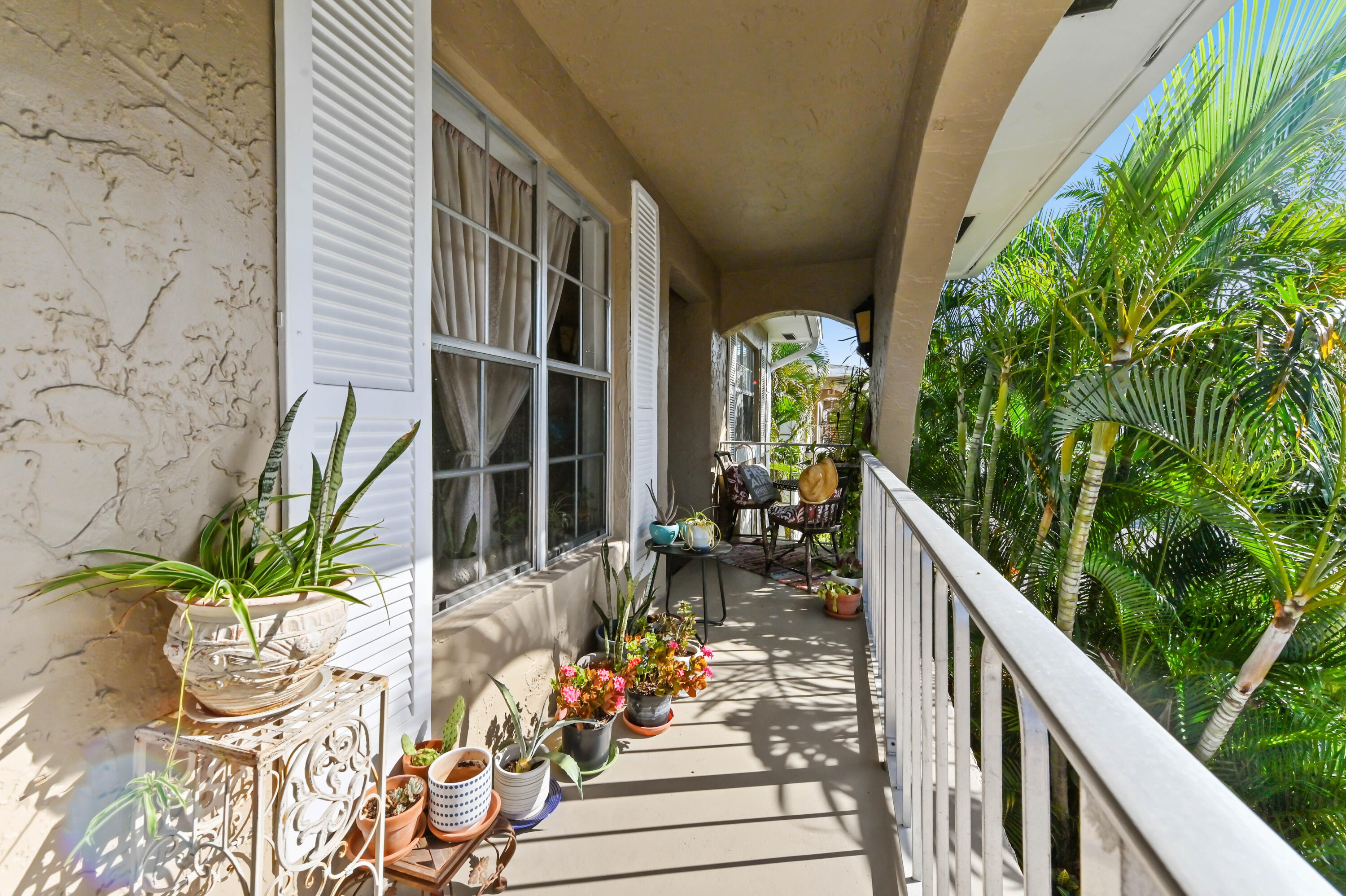 13960 Vía Flora, Unit H Delray Beach, FL 33484 - Photo 3 of 39 a view of a balcony with chairs potted plants