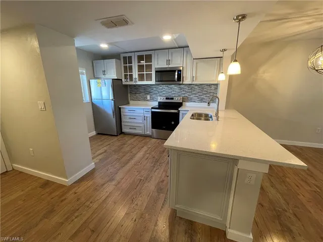 a kitchen with a sink a microwave a refrigerator and cabinets