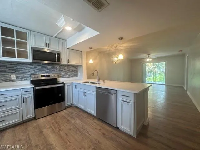 a large kitchen with stainless steel appliances granite countertop a stove a sink and a microwave