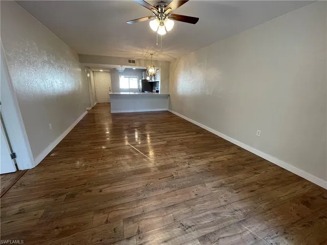 wooden floor in an empty room with a chandelier fan