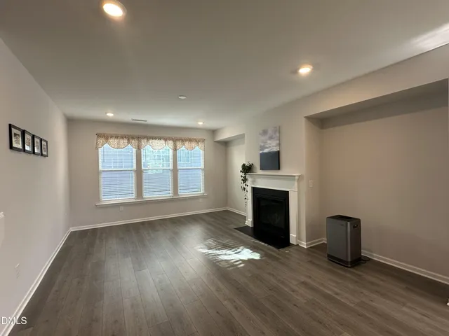 an empty room with wooden floor fireplace and windows