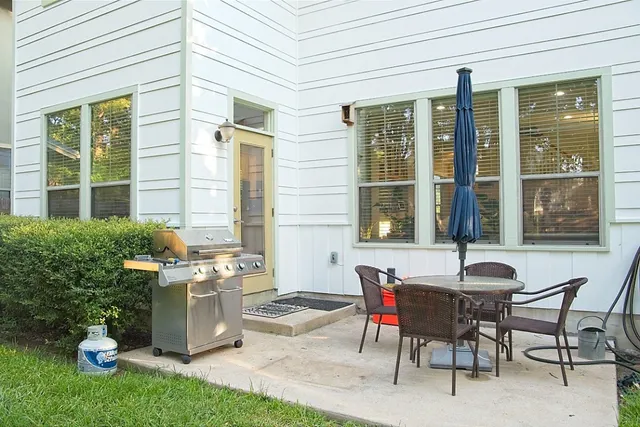 a patio with table and chairs and potted plants
