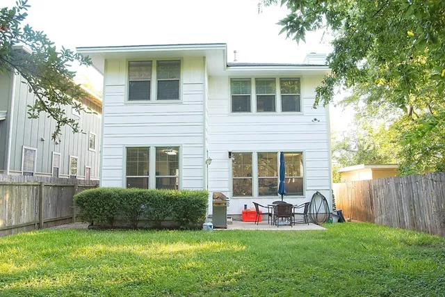 a backyard of a house with large tree and wooden fence