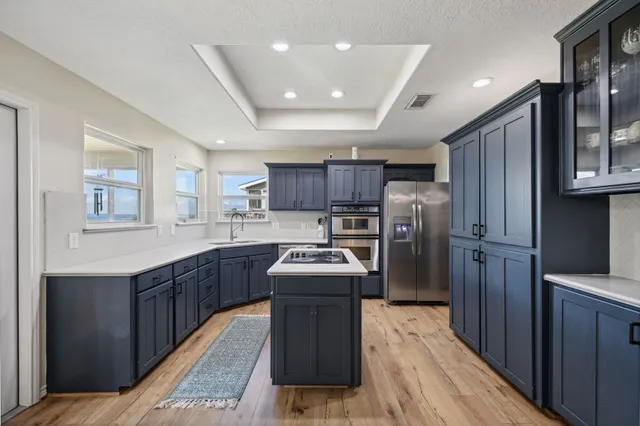 a kitchen with stainless steel appliances granite countertop a stove a sink dishwasher a refrigerator and a oven with wooden cabinets