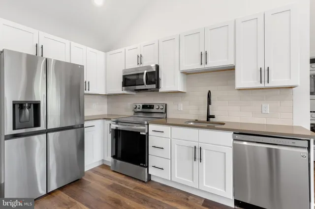a kitchen with granite countertop white cabinets and stainless steel appliances