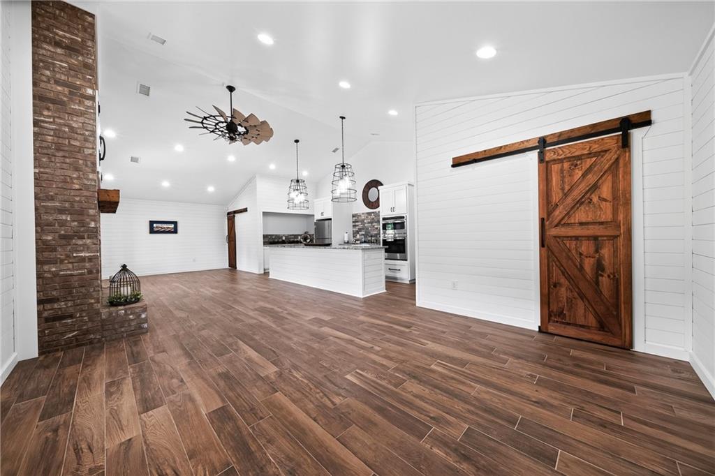 611 Padgetts Road Opelika, AL 36804 - Photo 50 of 64 Wood-finish flooring, white shiplap walls, brick-clad fireplace, vaulted ceiling, and a prominent barn door