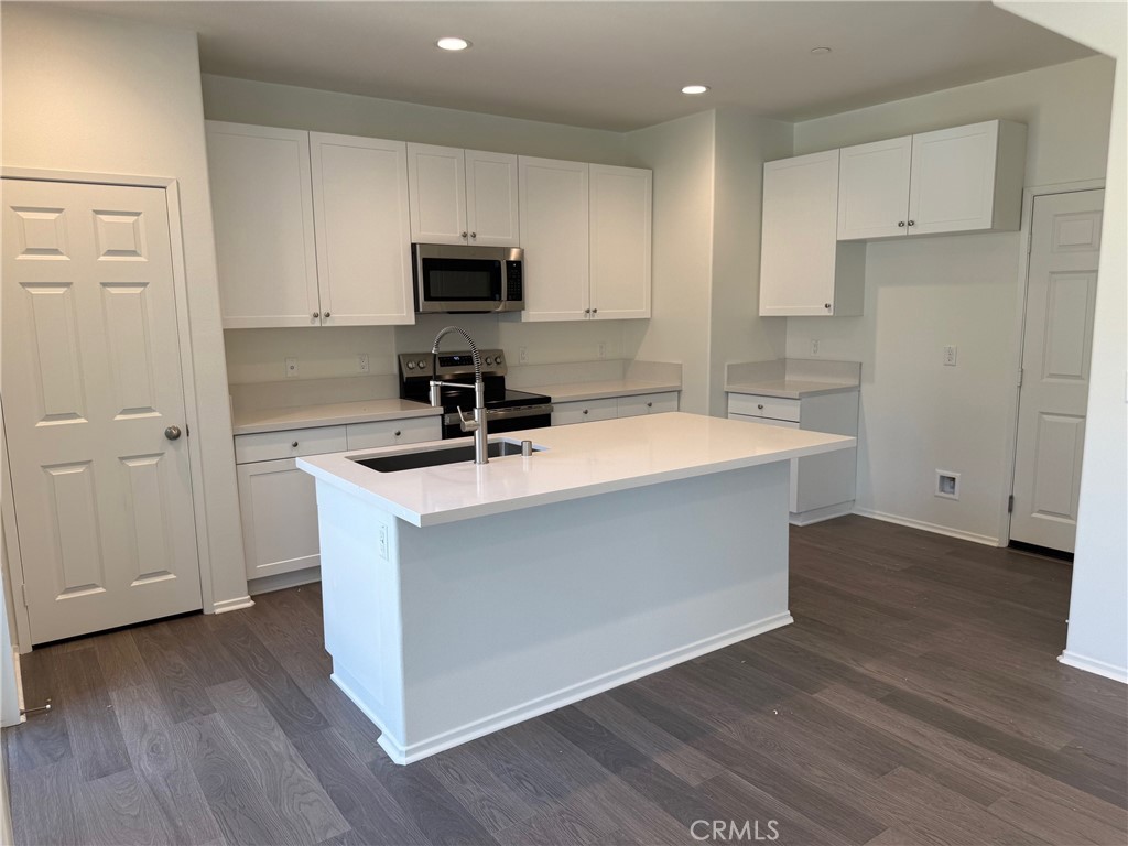 2246 Springmeadow Court Highland, CA 92346 - Photo 3 of 6 a kitchen with wooden floor white cabinets and stainless steel appliances