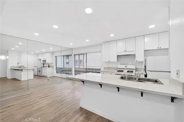 a large white kitchen with lots of counter space a sink appliances and cabinets