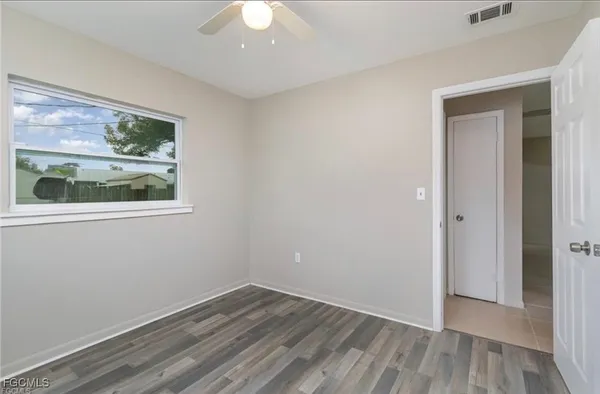 a view of an empty room with wooden floor and a window
