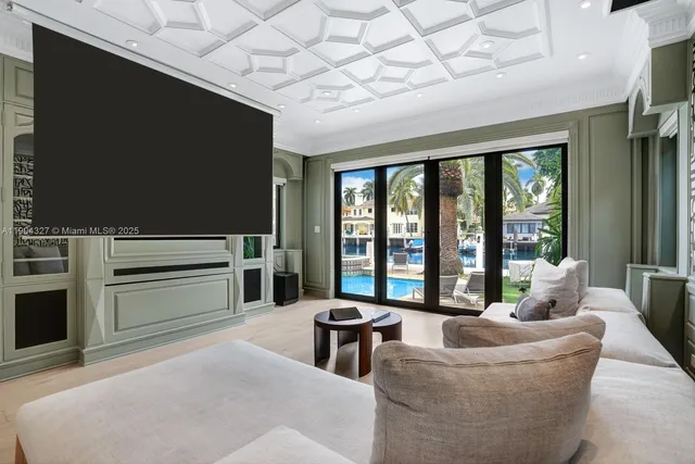 a living room with furniture a flat screen tv and floor to ceiling window