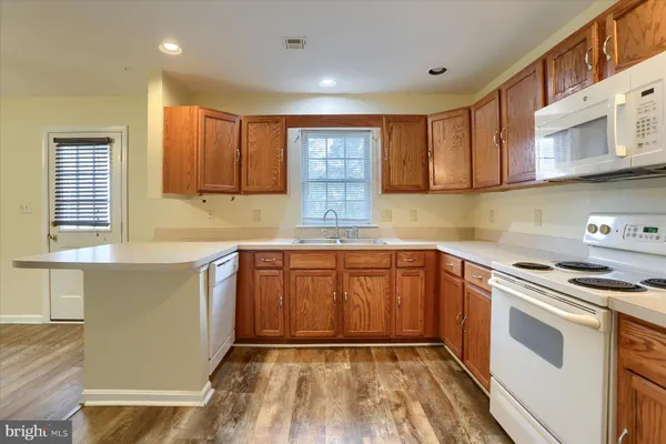 a kitchen with granite countertop wooden cabinets a stove a sink and dishwasher