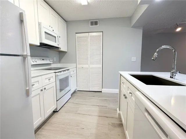 a kitchen with white cabinets and white appliances