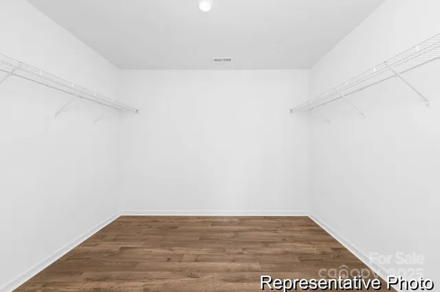 a walk in closet with wooden floor