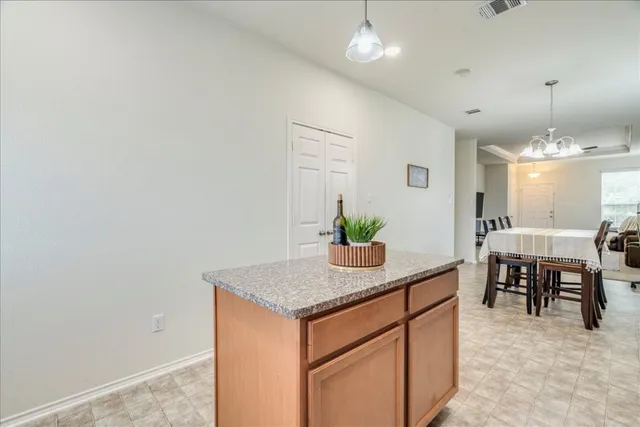 a kitchen with kitchen island granite countertop a stove top oven a sink dishwasher a dining table and chairs with wooden floor