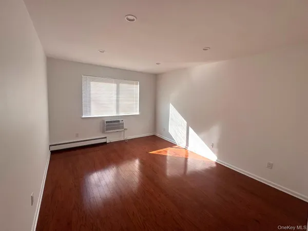 an empty room with wooden floor and window