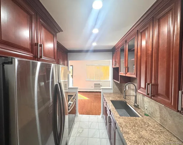 a kitchen with granite countertop stainless steel appliances a refrigerator sink and cabinets