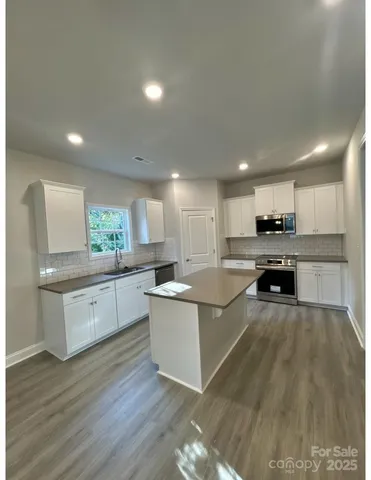 a large kitchen with a large counter top space a sink stainless steel appliances and cabinets