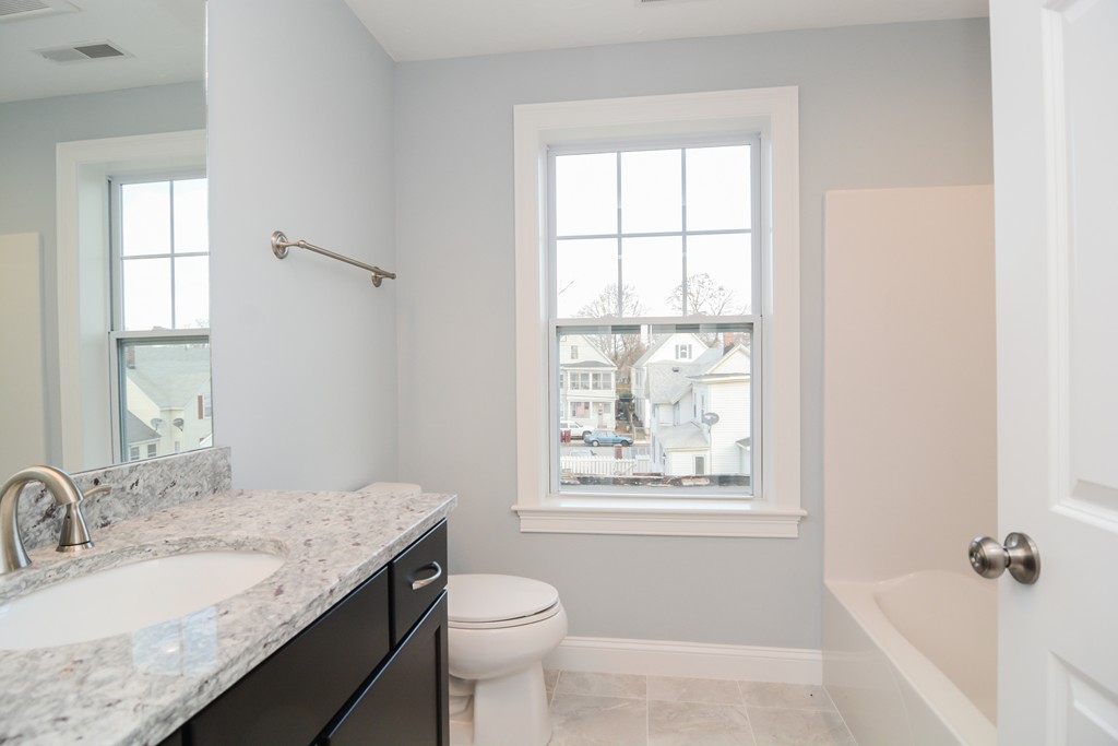 1400 Gorham Street, Unit 40 Lowell, MA 01852 - Photo 17 of 19 a bathroom with a granite countertop sink a toilet and a window